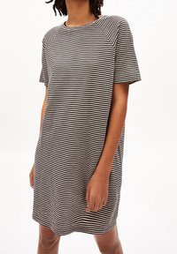 Pasiasta sukienka z krótkim rękawem w czerni i bieli, charakteryzująca się luźnym krojem, okrągłym dekoltem oraz miękkim materiałem bawełnianym.
