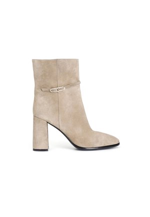 Stivaletto in camoscio beige con punta appuntita, tacco a blocco di altezza media e una fascia decorativa con un accento metallizzato. Texture liscia su tutta la superficie.