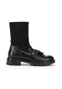 Botas negras hasta el tobillo con un upper tipo calcetín acanalado, puntera de cuero suave, detalle decorativo de borlas y hebillas, suela texturizada para mayor agarre.