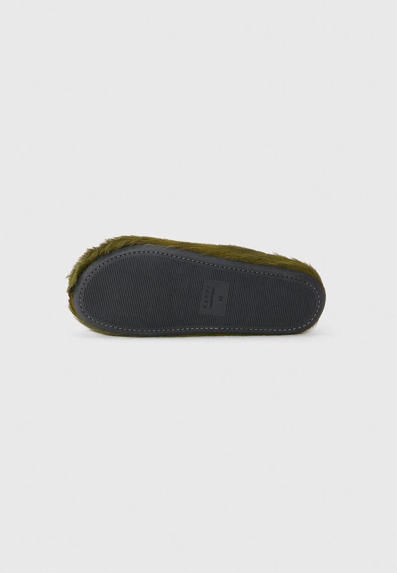 Pantofole verde oliva con una morbida tomaia in lana pelosa e una suola in gomma nera con un motivo testurizzato e dettagli di cucitura bianca.