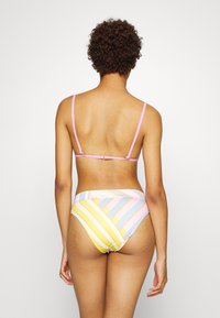 Fato de banho de duas peças com parte superior rosa de alças e parte inferior alta multicolorida com riscas em tons de amarelo, azul e rosa.