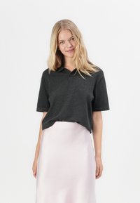 Polo shirt cinza escuro de manga curta com colarinho e três botões, combinado com uma saia de cetim rosa claro, com uma textura suave.