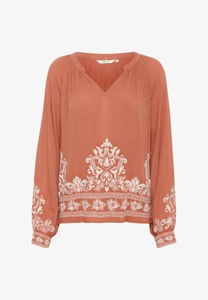 Rozsda színű blúz V-kivágással, hosszú ujjakkal, valamint fehér virágmintával az alján és az ujjakon. Könnyű, texturált anyag.