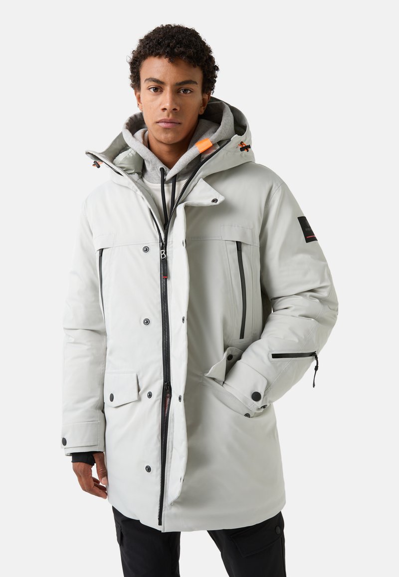 White insulated parka with a zip closure, large front pockets, and adjustable hood. Features black zipper accents and a grey inner lining.