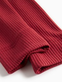 Kortsate, burgundia värvi kangas pehme ja tekstuuriga, volditud, et näidata selle pikkust ja kujundeid. Puhtad õmblused servadel rõhutavad disaini.