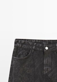 Jeans in denim nero con una finitura leggermente testurizzata, caratterizzati da un design standard a cinque tasche, chiusura con bottone e un'etichetta con marchio in vita.