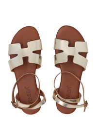 Gouden metallic platte sandalen met twee brede banden, met een uitsnijdingsontwerp. Bruin leren voetbed en een slanke enkelband.