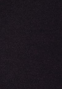 Gros plan sur un tissu texturé violet foncé avec de petits fils tissés en relief créant un motif quadrillé subtil.