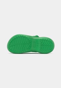 Green rubber shoe sole with textured tread pattern, featuring drainage holes and a slightly raised heel for traction and flexibility.