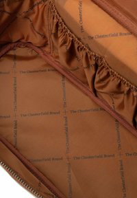 Forro interior marrón con un sutil estampado de "The Chesterfield Brand" y detalle fruncido a lo largo de los bordes.