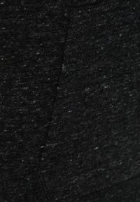 Närbild av mörkgrått texturerat tyg med subtila sömmar och mjukt, melerat mönster.