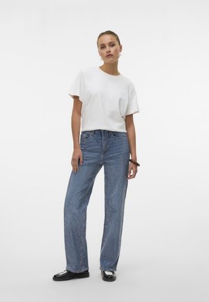 Witte kortemouw t-shirt gecombineerd met blauwe geruite wijde jeans en zwarte schoenen. De outfit heeft een ontspannen pasvorm en een minimalistisch ontwerp.