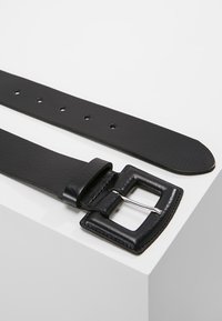 Black leather belt with a square silver buckle, featuring multiple holes for adjustment, smooth texture, and rounded tip.