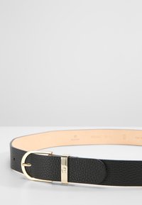 Cinturón de cuero negro con una superficie texturizada, que presenta una hebilla metálica dorada y un forro interior suave. Marcas de tamaño estándar visibles.