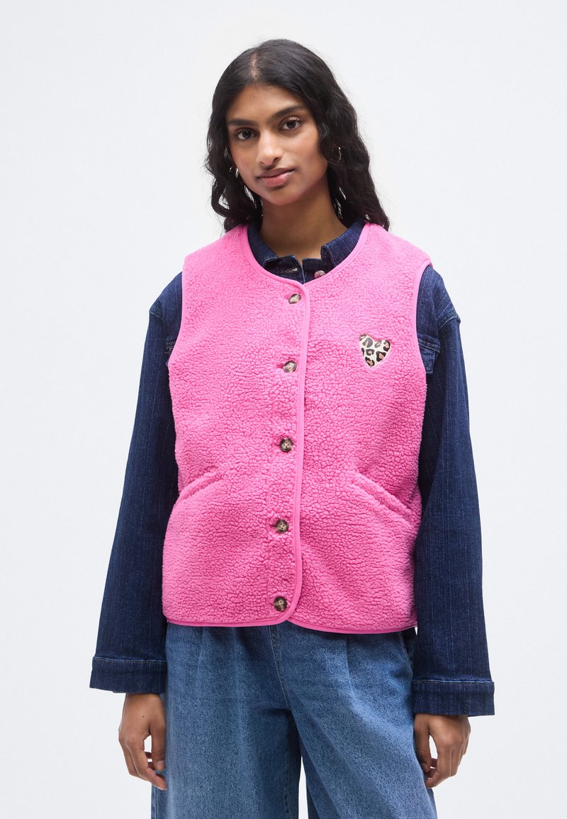 Ροζ γιλέκο από φλις με στρογγυλή λαιμόκοψη, κουμπιά μπροστά και δύο τσέπες. Διαθέτει καρδιά με λεοπάρ σχέδιο στο αριστερό στήθος.