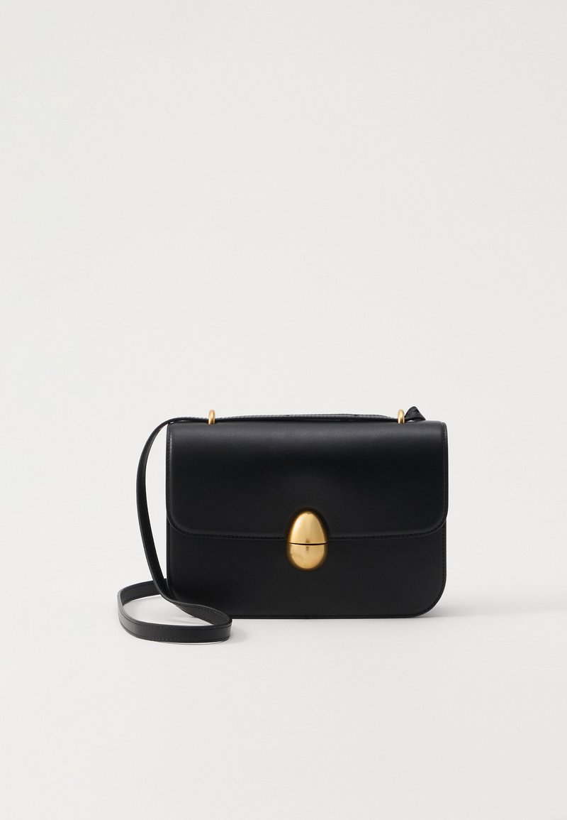 Bolsa de mão em couro preto com uma forma rectangular estruturada. Apresenta um fecho oval dourado e uma alça para o ombro fina. Textura suave.