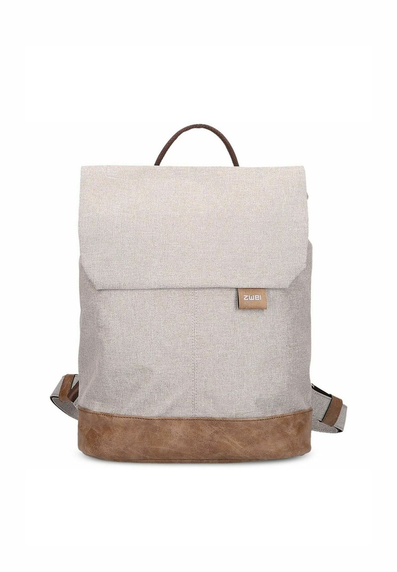 Mochila de tela gris claro con una base de cuero marrón. Cuenta con una solapa plegable y un asa superior, correas ajustables y una etiqueta de logo.