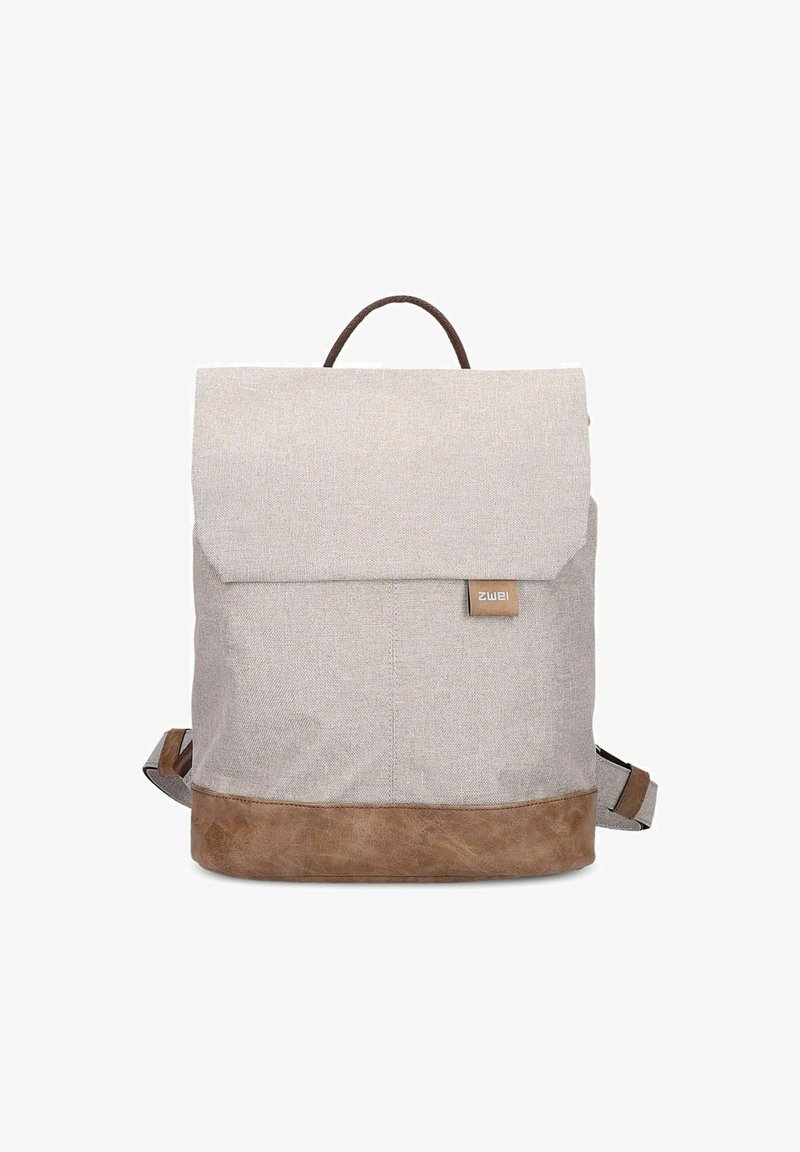 Mochila de tela gris claro con una base de cuero marrón. Cuenta con una solapa plegable y un asa superior, correas ajustables y una etiqueta de logo.