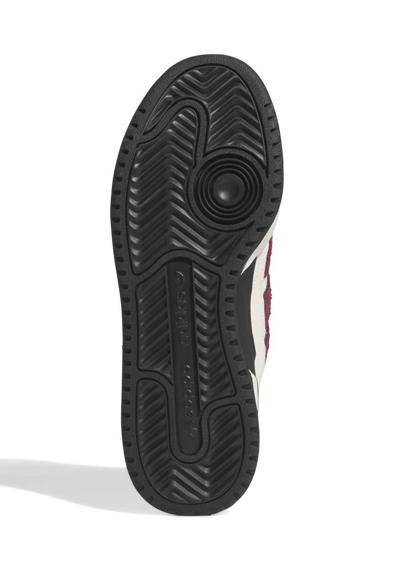 Semelle de chaussure en caoutchouc noir avec un motif texturé en zigzag, présentant un bouton circulaire et un logo en relief, souligné de touches crème et bordeaux.