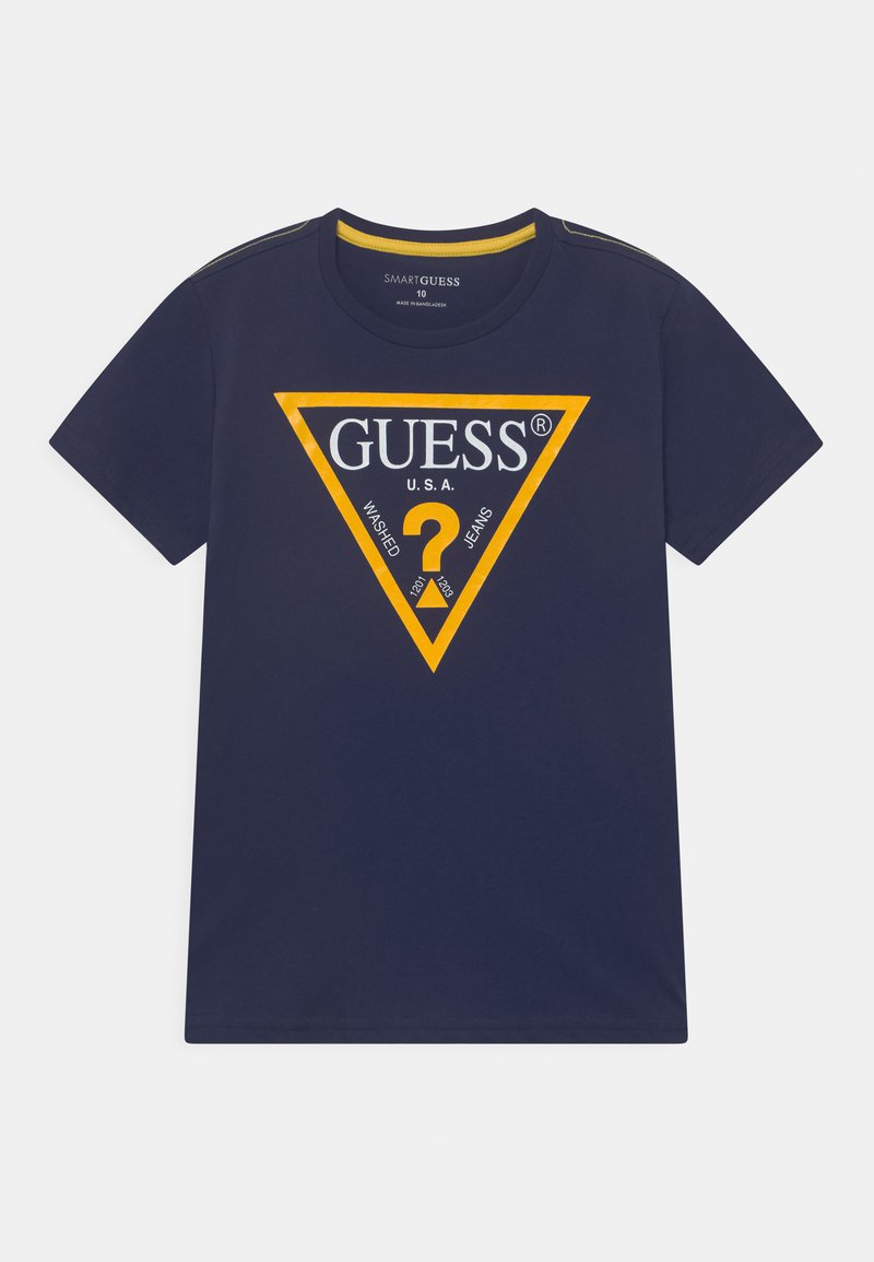 Mørkeblå bomulls T-skjorte med et stort gult trekantet logo med "GUESS" og tekst i hvitt. Kortermet, rund halsdesign.
