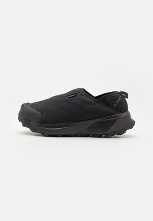 Czarne buty wsuwane z teksturowaną cholewką, solidną gumową podeszwą i okrągłym noskiem. Prosty detal z logo na boku.