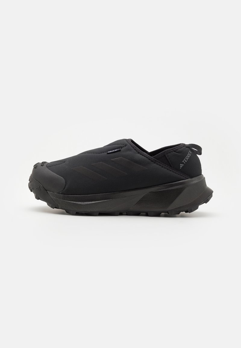 Black slip-on shoes featuring a textured upper, sturdy rubber sole, and a rounded toe design. Simple branding accent on the side.