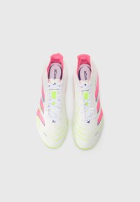 Witte sportschoenen met roze en neon groene accenten, voorzien van gebogen lijnen, drie strepen en een vetersluiting.