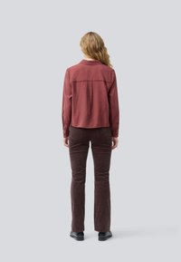 Maroon long-sleeve shirt with a back yoke design, paired with brown corduroy pants. The shirt has buttoned cuffs and a relaxed fit.