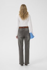 Hallid kõrge vöökohaga sirge säärega teksad, millel on kaks tagataskut. Kombineeritud valge pika varrukaga topi ja sinise aksessuaariga.