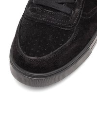 Melnas zamšādas kedas ar noapaļotu purngalu, teksturētu virsmu, plakaniem melniem auklām un gumijas zolēm, kurām ir teksturēts raksts.