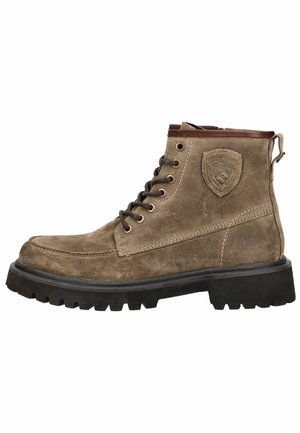 Stivali ankle in suede marrone con punta rinforzata, dettagli in pelle marrone a contrasto, occhialini in metallo e suola in gomma testurizzata.