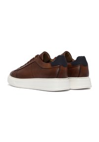 Sneakers in pelle marrone con una superficie liscia, dettagli testurizzati, suole in gomma bianca e tappi del tallone blu scuro. Presentano un design low-top.