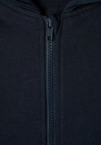 Vêtement zippé noir en tissu en coton, avec une fermeture éclair lisse et une doublure texturée. La fermeture éclair est sombre et bien intégrée.