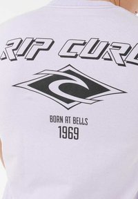 Weißes T-Shirt mit schwarzem Text "RIP CURL" und einem Wellenlogo. Das Design auf der Rückseite enthält "BORN AT BELLS" und "1969" in fetter Schrift. Aus weichem Baumwollstoff.