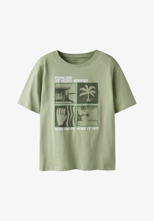 T-shirt vert clair avec quatre graphismes carrés : planches de surf, palmier, main avec des vagues et scène de plage ; texte "Pipeline à Oahu Hawaii."