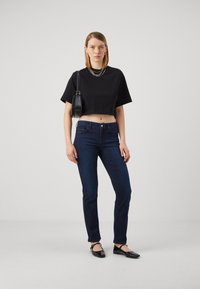 Musta lyhythihainen t-paita, tummansiniset tiukasti istuvat farkut ja mustat ballerinat. Hopeaketjun kaulakoru. Minimalistinen musta olkalaukku. Silkkiset kankaan tekstuurit.