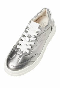 Sneaker metallica argento con punta arrotondata, lacci bianchi, pannelli laterali testurizzati e suola bianca imbottita. Presenta il logo sulla linguetta.