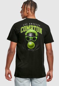 Tricou negru din bumbac, cu un imprimeu grafic al unui personaj cu păr verde aprins și ochelari de soare, textul "LOS ANGELES COMPTON" deasupra.