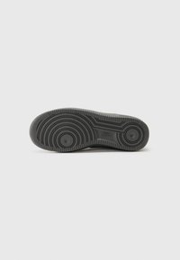 Black rubber sneaker sole with circular and wavy tread patterns. Features two circular indentations and a smooth center section.