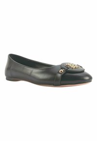 Mary Janes de piel negra con puntera redondeada, un detalle decorativo en dorado, y una textura suave con un diseño minimalista.