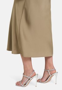 Silberne High Heel Sandalen mit einem Riemchen-Design und Strass-Akzenten. Der Absatz ist elegant, mit einer nudefarbenen Sohle und einem schimmernden Finish.