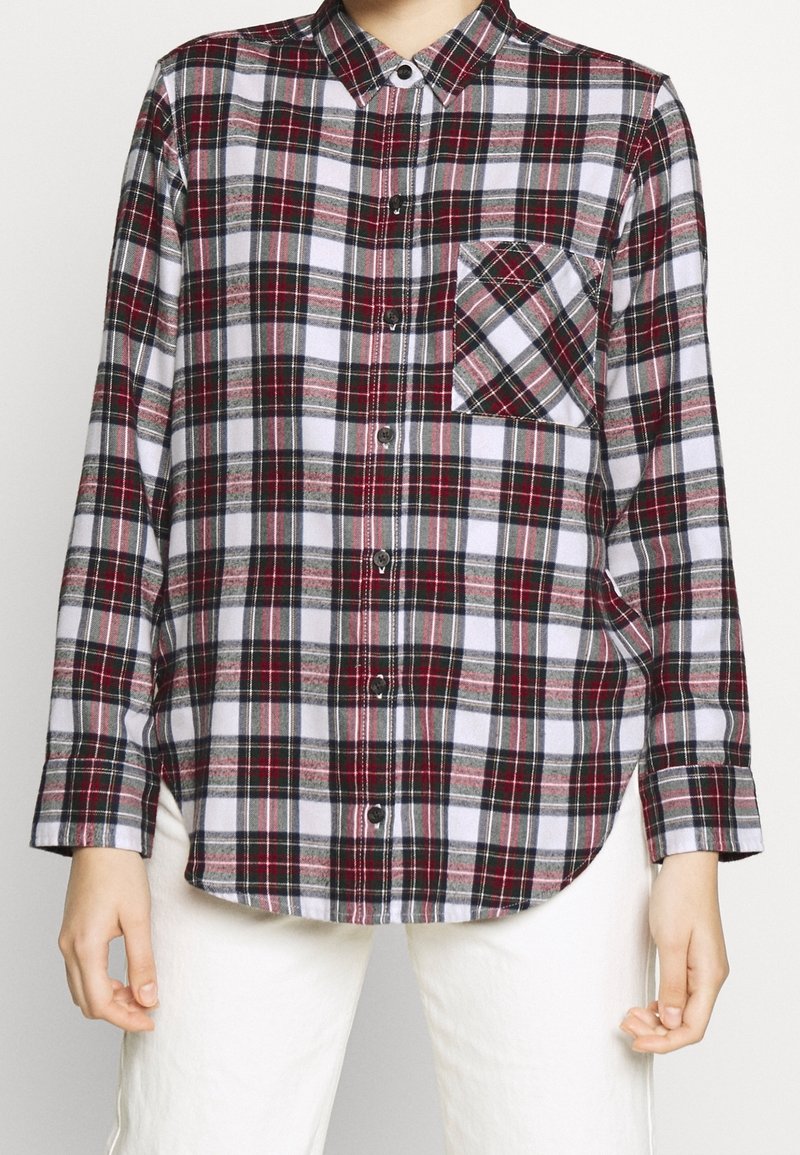 Camisa de cuadro en rojo, negro y blanco. Presenta un bolsillo en el pecho y mangas largas con puños abotonados. Tejido suave, dobladillo curvado.