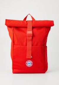 Rød rulletopp ryggsekk laget av slitesterk stoff, med en kontrastrem og FC Bayern München-logo på frontlommen.