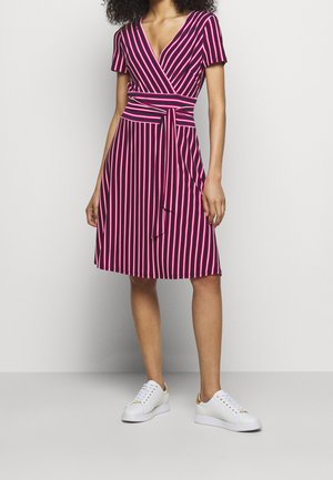 Robe portefeuille à rayures rose et marine, manches courtes, col en V, taille cintrée avec un lien à nouer, jupe évasée, associée à des baskets blanches.