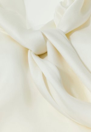 Glatter, cremefarbener Stoff, der gesammelt und verdreht ist, um weiche Falten und Kurven mit seidiger Textur zu bilden.