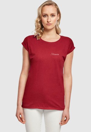 Rød kortærmet t-shirt lavet af blødt stof, med rund halsudskæring og en lille hvid hjerte og tekstdetalje på forsiden.