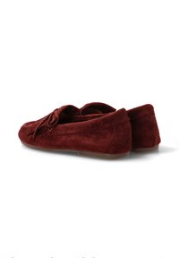 Par de mocasines de ante rojo oscuro con detalles de borlas y suelas de goma marrón planas, mostrados desde un ángulo trasero.