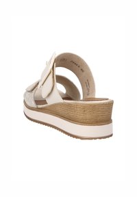 Sandales à plateforme blanches avec un dos ouvert, présentant un talon brun texturé et un bout lisse et arrondi. Accentué d'un nœud décoratif.