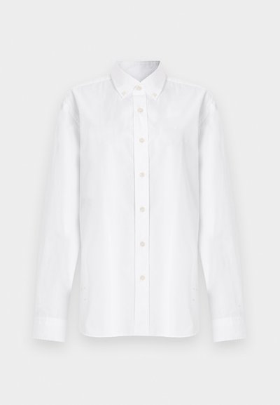 Λευκό πουκάμισο με μακριά μανίκια, κουμπώνει μπροστά και έχει γιακά, με επτά εμφανείς κουμπιά, το οποίο παρουσιάζεται πάνω σε απλό λευκό φόντο.