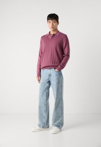 Bordeaux ripsaste polo majica dolgih rokavov s ovratnikom, kombinirana s svetloblue širokimi jeans hlačami in belimi supergami.